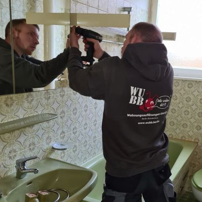 Mitarbeiter der WUBB baut einen Badspiegel bei einer Wohnungsaufl&ouml;sung in Berlin Spandau ab.